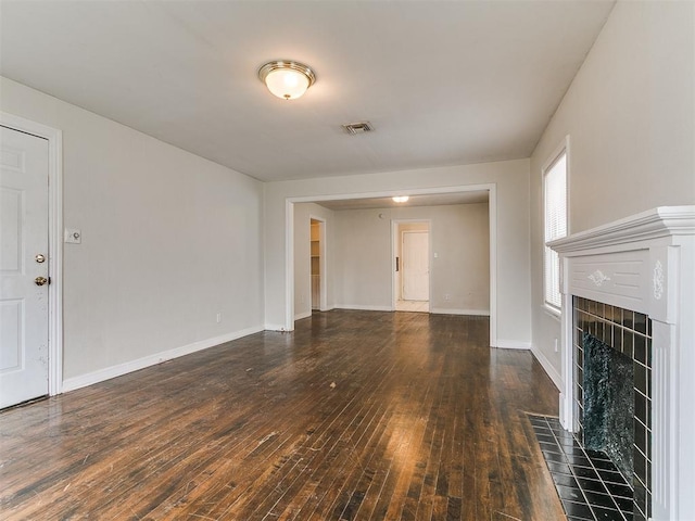 unfurnished living room featuring visible vents, a fireplace, baseboards, and wood-type flooring