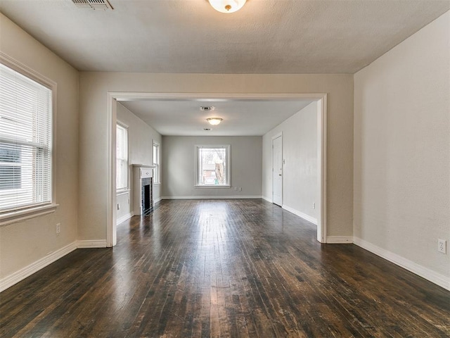 unfurnished living room featuring a fireplace, dark wood-type flooring, and baseboards