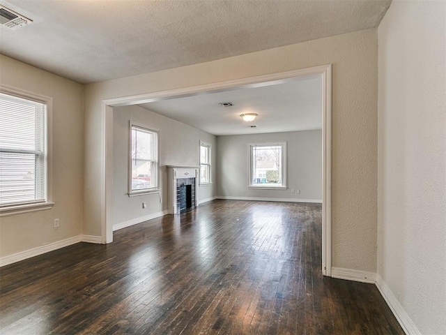 unfurnished living room featuring visible vents, dark wood-type flooring, and baseboards