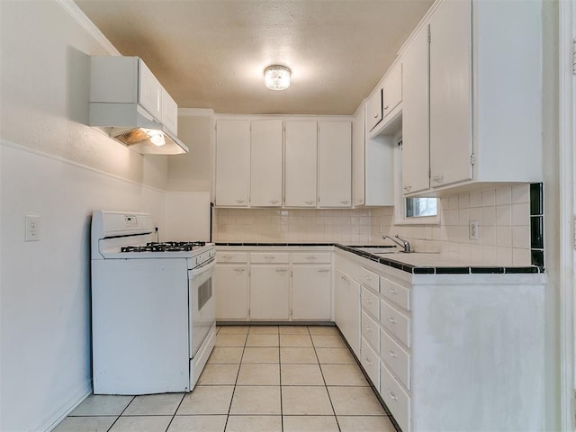 kitchen with light tile patterned floors, gas range gas stove, backsplash, and a sink