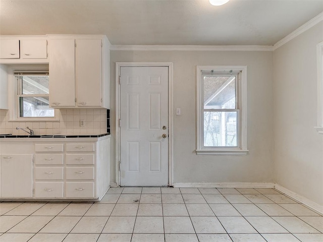 kitchen featuring white cabinetry, tile countertops, crown molding, decorative backsplash, and baseboards