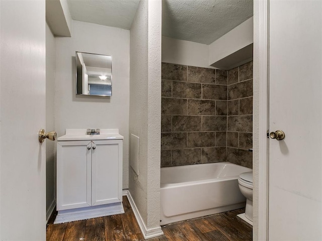 bathroom with vanity, wood finished floors, tub / shower combination, a textured ceiling, and toilet