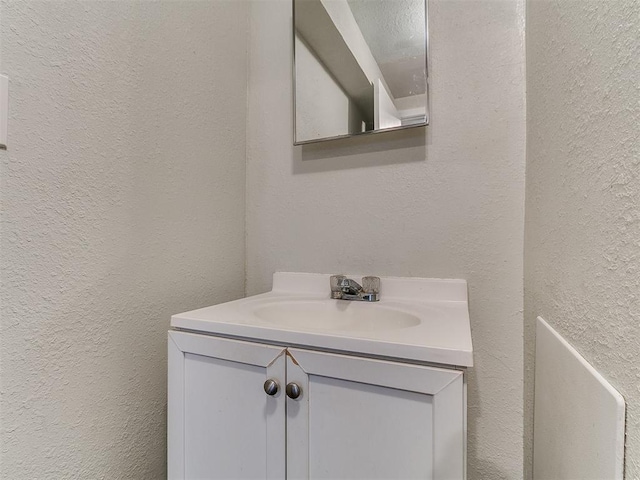 bathroom with vanity and a textured wall