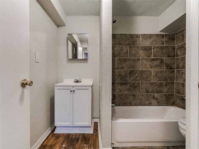 bathroom with toilet, wood finished floors, shower / bath combination, baseboards, and vanity