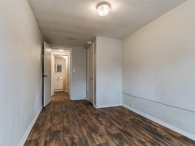 spare room featuring baseboards, a textured ceiling, and dark wood-style flooring