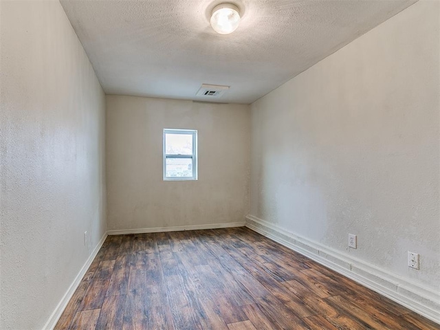 unfurnished room with visible vents, a textured ceiling, wood finished floors, and a textured wall