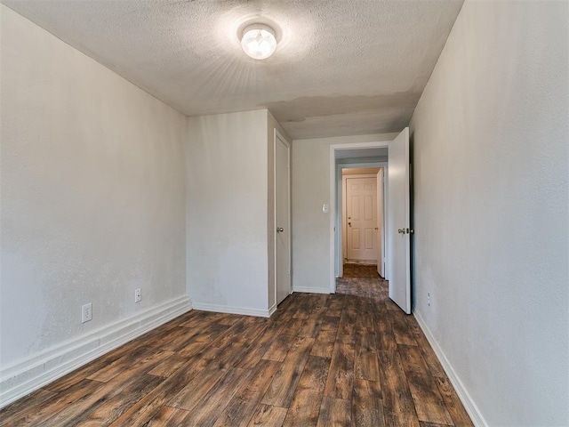 empty room with a textured ceiling, baseboards, and wood finished floors