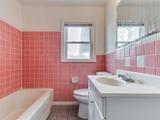 bathroom featuring tile patterned floors, toilet, a washtub, tile walls, and vanity