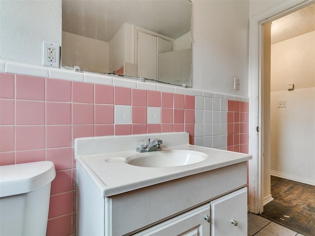 bathroom featuring toilet, tile walls, and vanity