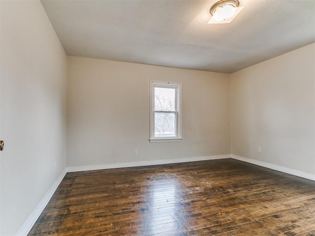 spare room with hardwood / wood-style flooring, baseboards, and a textured ceiling