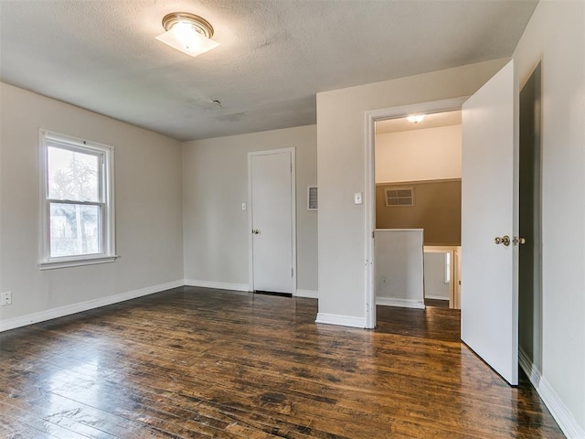 spare room featuring visible vents, baseboards, a textured ceiling, and hardwood / wood-style floors