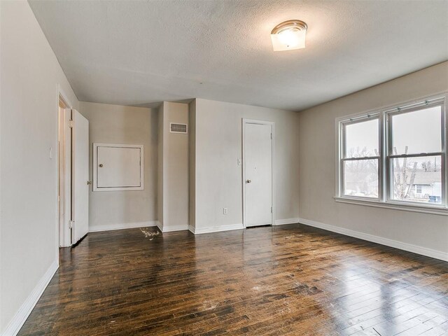 unfurnished room with visible vents, baseboards, and wood-type flooring