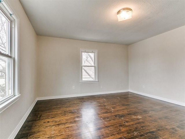 spare room featuring baseboards and dark wood-style flooring