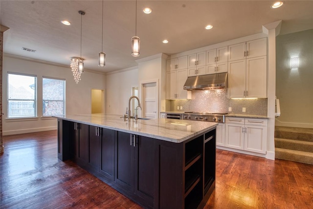 kitchen with under cabinet range hood, white cabinetry, stainless steel gas stovetop, and a sink