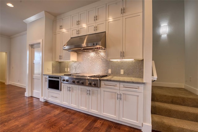 kitchen with under cabinet range hood, tasteful backsplash, dark wood-style floors, appliances with stainless steel finishes, and crown molding