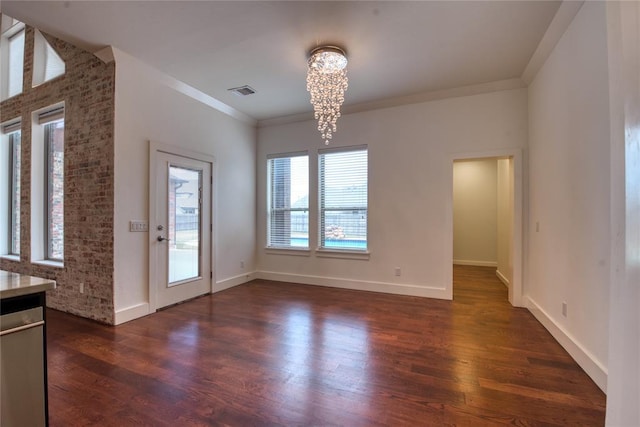 unfurnished dining area featuring an inviting chandelier, visible vents, dark wood-style flooring, and ornamental molding