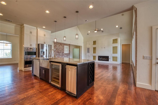 kitchen with visible vents, a kitchen island with sink, beverage cooler, open floor plan, and stainless steel appliances