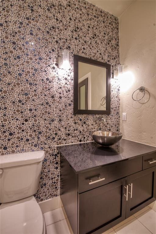 bathroom with tile patterned flooring, toilet, vanity, and a textured wall