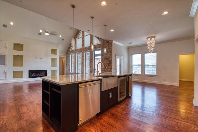 kitchen featuring a sink, stainless steel dishwasher, a glass covered fireplace, dark wood-style floors, and open floor plan