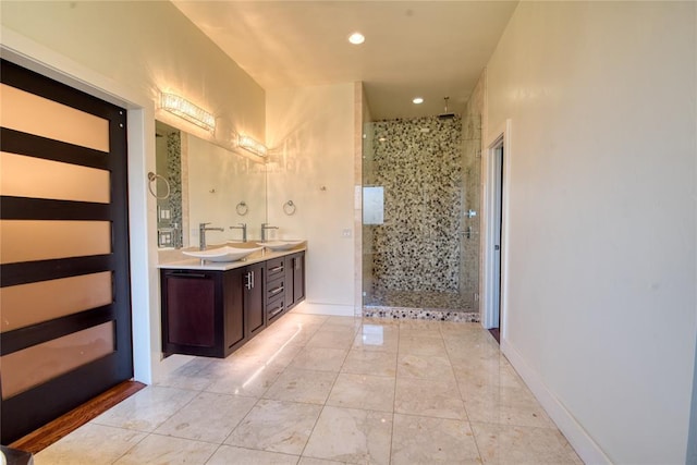 bathroom with a shower stall, double vanity, baseboards, and a sink