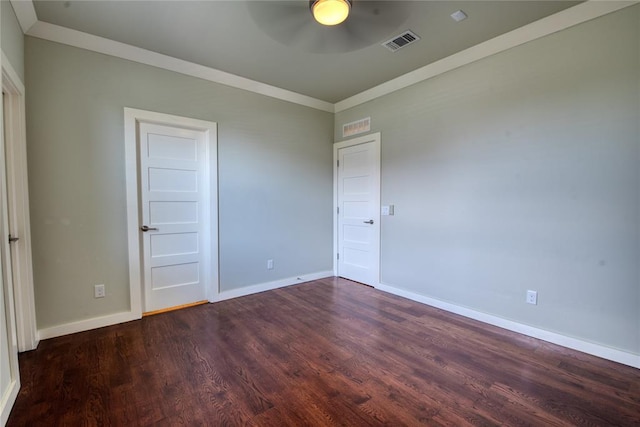 unfurnished bedroom with visible vents, baseboards, dark wood-type flooring, and crown molding