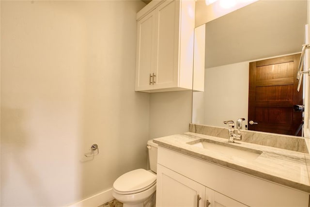 half bathroom featuring baseboards, toilet, and vanity