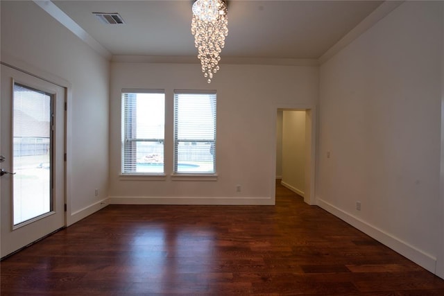 unfurnished room featuring visible vents, a notable chandelier, ornamental molding, and dark wood-style flooring