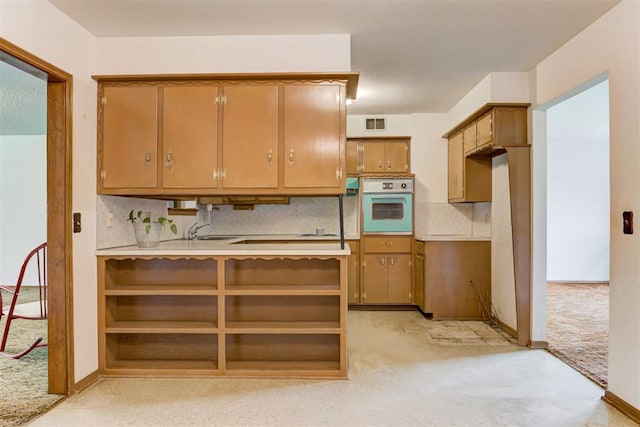 4801 Del Crest Dr, Del City, OK 73115 - kitchen featuring white oven, light colored carpet, brown cabinetry, and light countertops