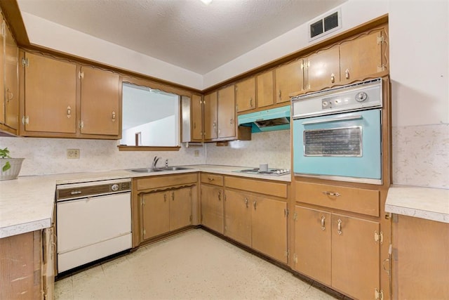 4801 Del Crest Dr, Del City, OK 73115 - kitchen with white appliances, under cabinet range hood, light countertops, tasteful backsplash, and brown cabinets