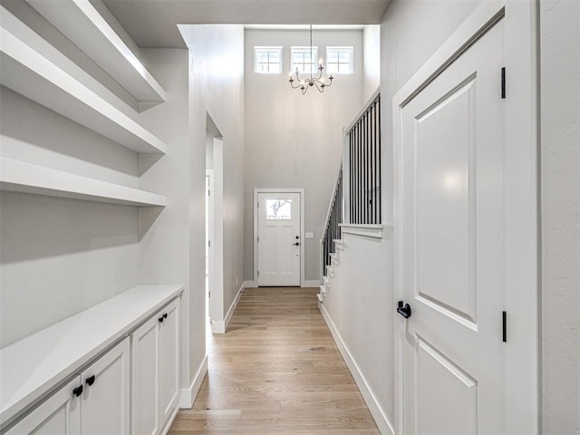 foyer entrance featuring light wood-type flooring, baseboards, and a notable chandelier