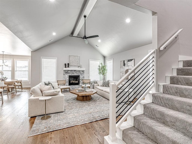 living area featuring beam ceiling, stairs, a ceiling fan, and wood finished floors