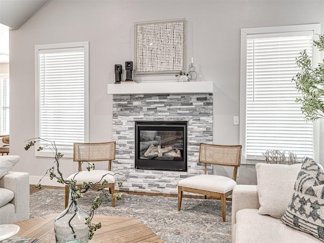 living room featuring a glass covered fireplace, baseboards, and vaulted ceiling