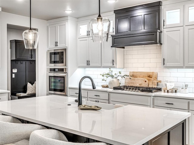 kitchen featuring decorative backsplash, appliances with stainless steel finishes, a breakfast bar, and custom range hood