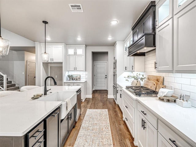 kitchen featuring visible vents, dark wood-style flooring, stainless steel appliances, a sink, and white cabinets