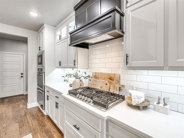 kitchen featuring light countertops, dark wood-style floors, premium range hood, and stainless steel gas cooktop