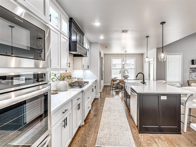 kitchen with light countertops, light wood-style flooring, visible vents, and stainless steel appliances