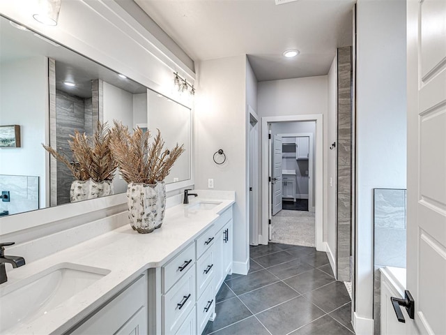 full bathroom featuring double vanity, tile patterned flooring, tiled shower, and a sink