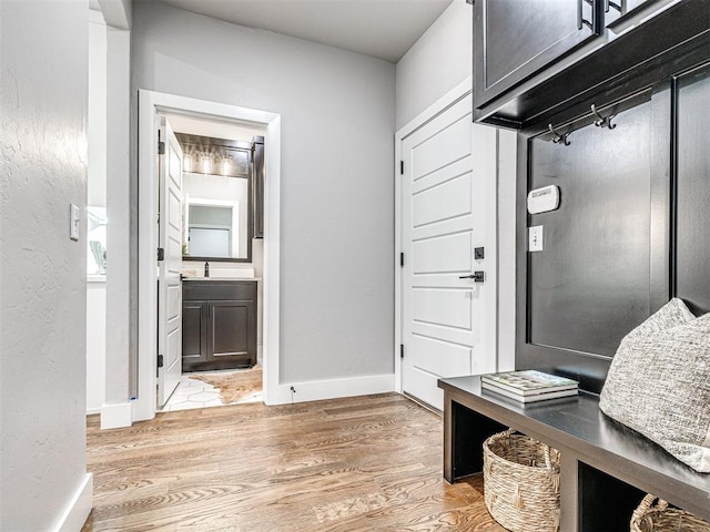 entryway featuring a textured wall, baseboards, and light wood finished floors