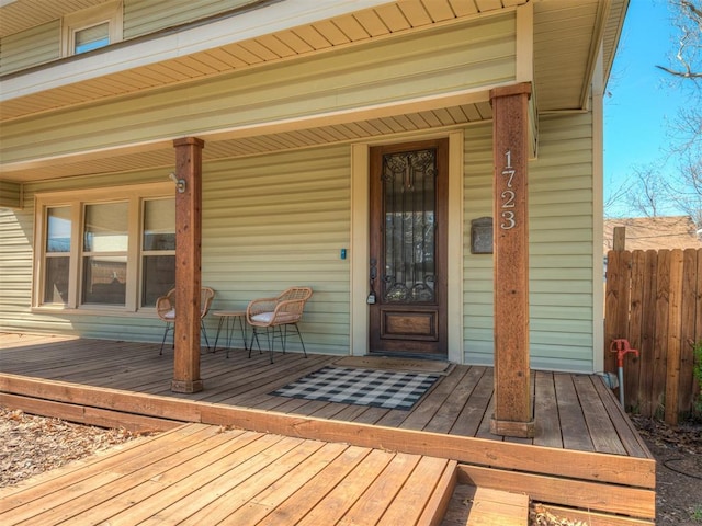 entrance to property with a porch and fence