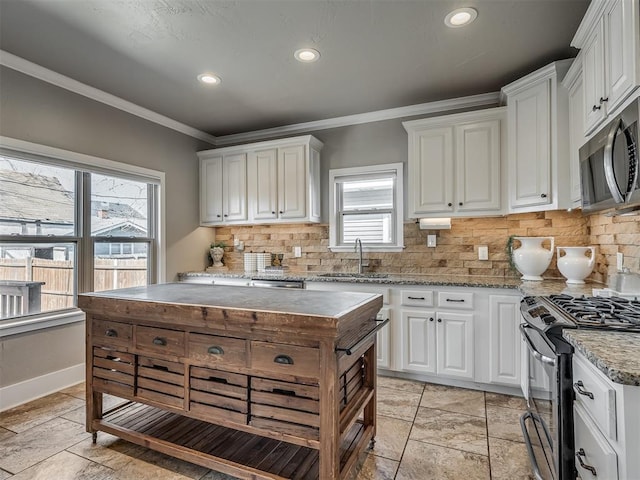 kitchen with crown molding, appliances with stainless steel finishes, white cabinets, wood counters, and a sink