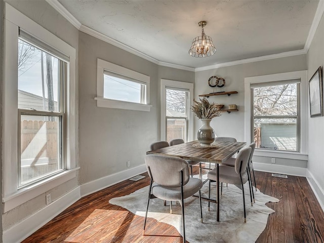 dining space featuring a healthy amount of sunlight, baseboards, an inviting chandelier, and wood finished floors