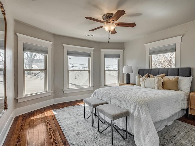 bedroom with visible vents, multiple windows, dark wood-type flooring, and baseboards