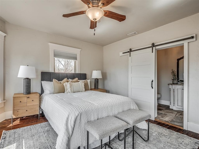 bedroom featuring visible vents, dark wood-type flooring, a barn door, baseboards, and ceiling fan