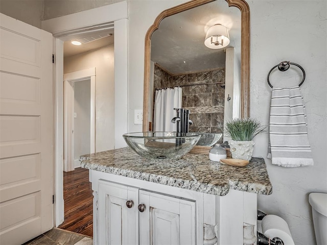 full bath featuring visible vents, a shower with curtain, toilet, wood finished floors, and vanity