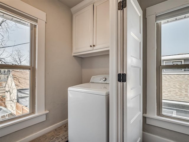 clothes washing area featuring washer / clothes dryer, cabinet space, plenty of natural light, and baseboards