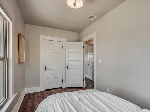 bedroom featuring visible vents, baseboards, wood finished floors, a textured wall, and a closet