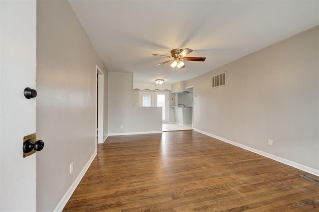 spare room with baseboards, wood finished floors, visible vents, and ceiling fan