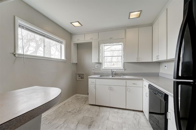 kitchen featuring a sink, black appliances, light countertops, marble finish floor, and a wealth of natural light