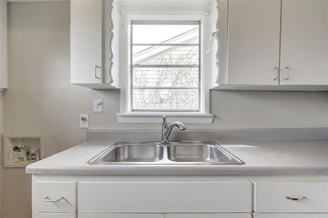 kitchen featuring white cabinets, light countertops, and a sink