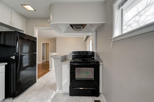 kitchen with black appliances, exhaust hood, light countertops, and white cabinetry